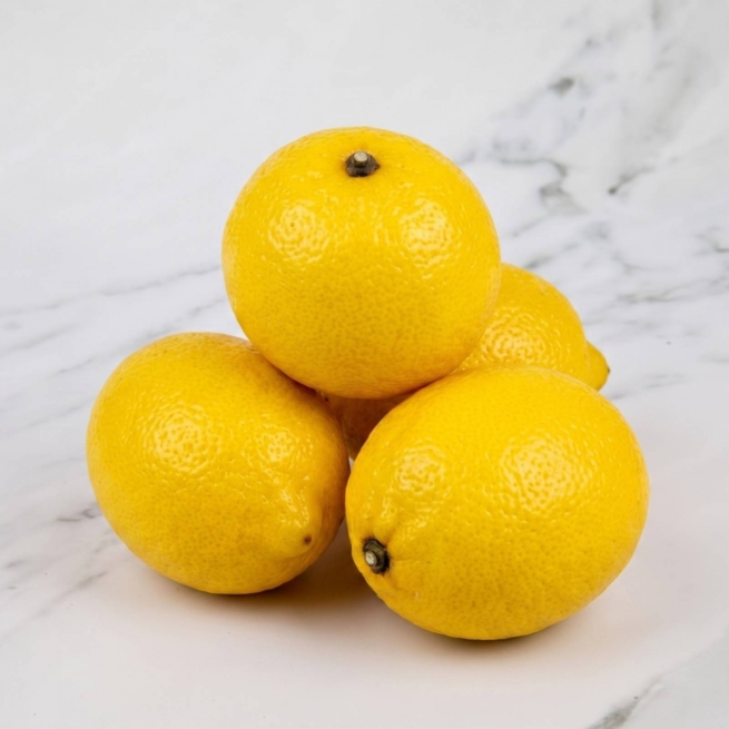Four bright, high-quality fresh yellow lemons displayed beautifully at the Eric Lyons marble countertop.